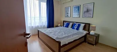 a bedroom with a bed with blue pillows and a window at Imperial Sea View in Burgas City