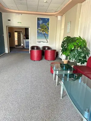 a lobby with red chairs and tables and plants at Хотел Модева in Chernomorets