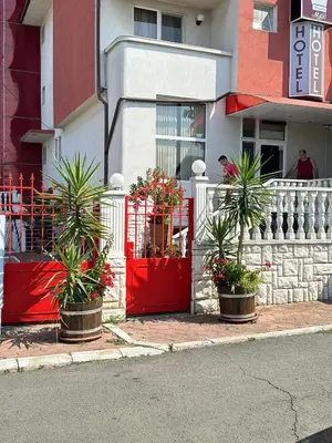 a red gate with potted plants in front of a building at Хотел Модева in Chernomorets