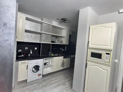 a kitchen with white cabinets and a washer and dryer at Апартамент Велкови in Tsarevo
