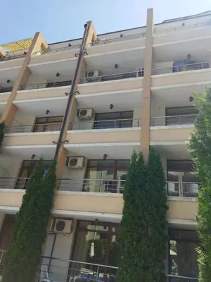 an apartment building with trees in front of it at Святая Елена in Sunny Beach