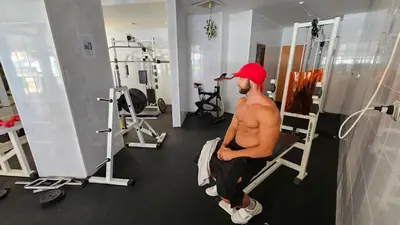 a shirtless man sitting on a bench in a gym at Apartment 16 - Rainbow Holiday Complex in Sunny Beach