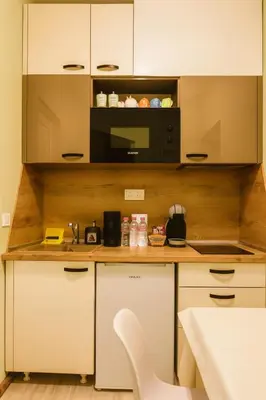 a kitchen with white cabinets and a black microwave at KOKO House in Varna City