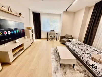 a living room with a couch and a flat screen tv at Beach Please Apartment in Burgas City