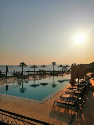 a pool with chairs and umbrellas next to the ocean at Onyx Sveti Vlas частни апартаменти in Sveti Vlas
