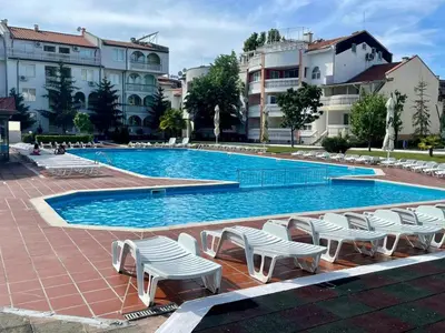 a large swimming pool with white chairs and buildings at Bravo 1 in Sunny Beach