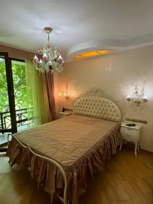 a bedroom with a large bed and a chandelier at Апартамент в Лозенец, Oasis Resort and Spa in Lozenets