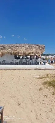 a group of picnic tables and a straw umbrella on the beach at Sunrise Apartment 14 in Obzor