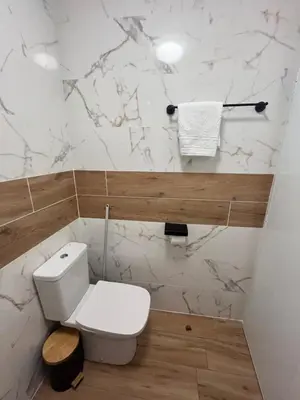 a bathroom with a white toilet and marble walls at Къща за гости Сирената in Sozopol