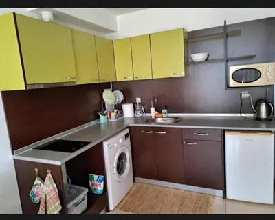 a kitchen with yellow cabinets and a washing machine at Уютная студия на Солнечном берегу in Sunny Beach