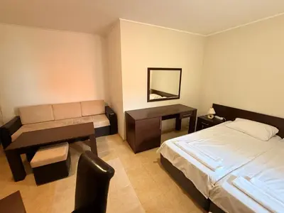 a hotel room with a bed and a desk and a couch at South Beach Vigo Studio in Nesebar