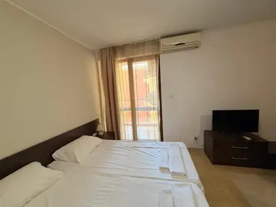 a bedroom with a white bed and a television at South Beach Vigo Studio in Nesebar