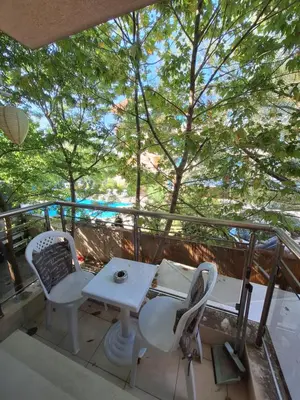 a balcony with a table and chairs and trees at Бобс апартаменти 1 in Kiten