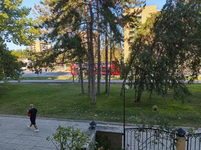 a man walking through a park with a red bus at Royal Sun - Vaio - 1BR Apt with Balcony in Sunny Beach