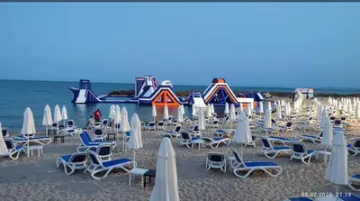 a bunch of chairs and umbrellas on a beach at Апартамент у моря in Nesebar