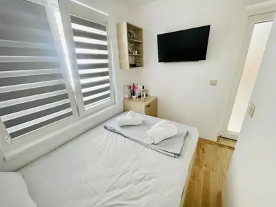 a white bedroom with a bed and a window at The Secret Tale in Varna City