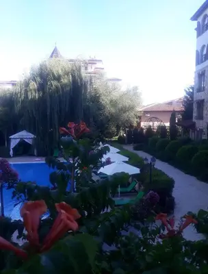 a garden with a swimming pool and some flowers at Эстебан с 2 спальнями in Nesebar