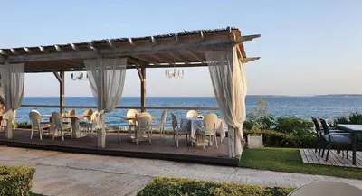 a gazebo with tables and chairs and the ocean at Каса реал с 2 спальнями 2 этаж in Sveti Vlas