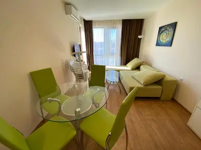 a living room with a glass table and green chairs at Premier Fort Beach in Sveti Vlas