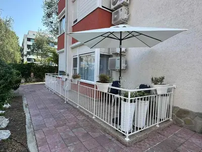 a patio with an umbrella and plants in front of a building at Apartment in Sunny Fort in Sunny Beach
