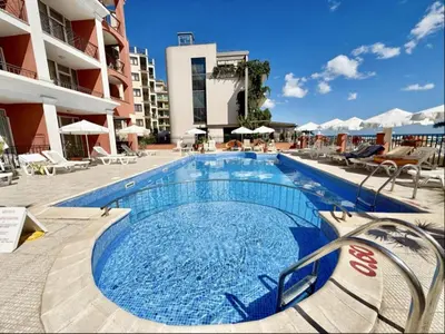 a large swimming pool with chairs and a building at Carina Beach - Menada Apartments in Sunny Beach