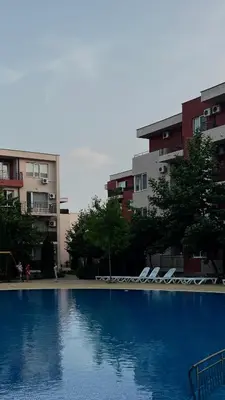 a large swimming pool with lounge chairs and buildings at Sunny Beach Fort Noks Orchid Apartment in Sunny Beach