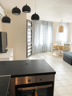 a kitchen with a black counter top and a living room at Cozy apartment at the heart of Burgas in Burgas City
