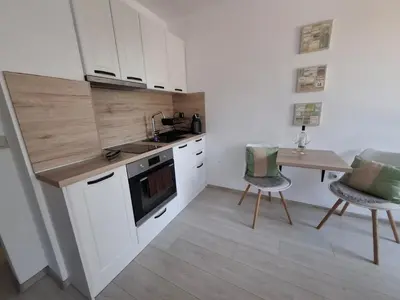 a kitchen with white cabinets and a table and chairs at Sweet tiny house-central studio in Varna City
