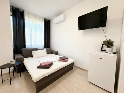 a small room with a bed and a tv on the wall at Sweet tiny house-central studio in Varna City