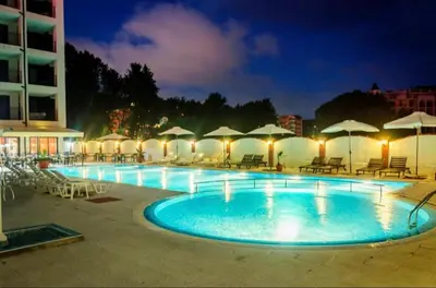 a swimming pool with chairs and umbrellas at night at Luxury Studio B02 SB in Sunny Beach