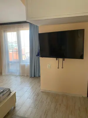 a living room with a large flat screen tv on the wall at Къща за гости DOSH in Sozopol