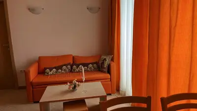 a living room with an orange couch and a table at 1BD Apartment in Royal Sun Complex, Sunny Beach by Flat Mаnager in Sunny Beach