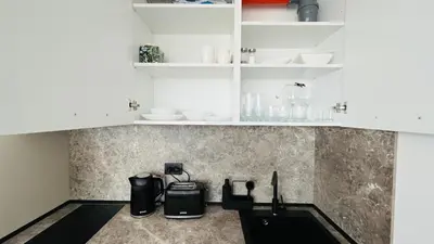 a kitchen with white cabinets and black appliances at JADORE Secret Garden Panoramic Studio in Sunny Beach