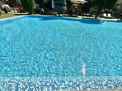 a large blue swimming pool with a tile floor at Emerald Paradise - Menada Apartments in Sunny Beach
