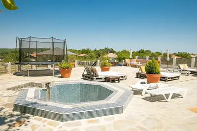 a patio with a pool and chairs and a table at Luxury, private pool, sauna, beach! in Banya