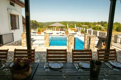 a wooden table with chairs and a swimming pool at Luxury, private pool, sauna, beach! in Banya