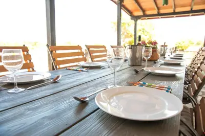a wooden table with plates and wine glasses on it at Luxury, private pool, sauna, beach! in Banya