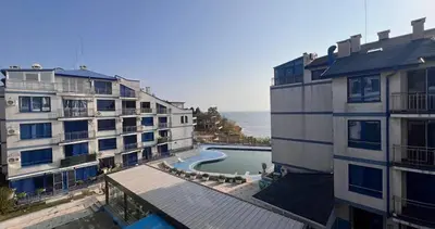 an apartment building with a swimming pool next to a building at Двустаен апартамент с морска панорама в Blue Bay Palace in Pomorie