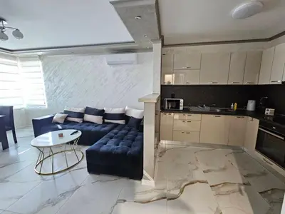 a living room with a blue couch and a kitchen at Small Central Flat - Walk to Station & Cathedral in Varna City