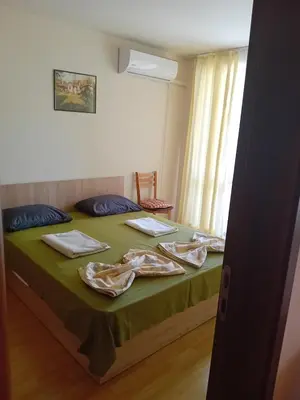 a bedroom with a bed with green sheets and a window at Двустаен апартамент във Виго Панорама Несебър in Nesebar
