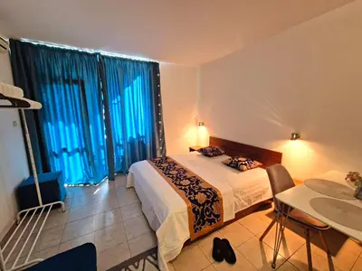 a hotel room with a bed and a table and windows at complex Rose Residence Studio in Sunny Beach
