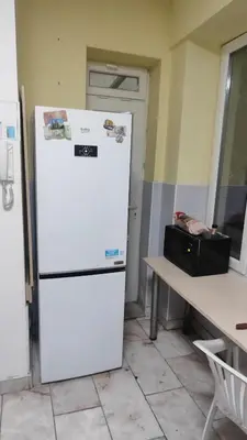 a white refrigerator in a room with a table at Стая лидер хаус in Varna City