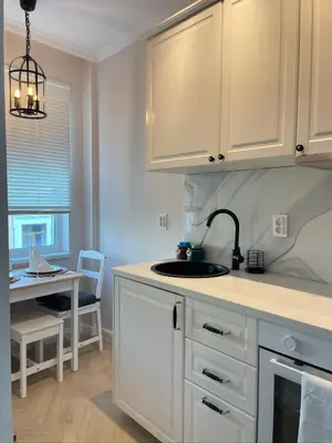 a kitchen with white cabinets and a sink and a table at Nearby the Sea- Elegant Retreat in Varna in Varna City