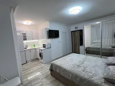 a bedroom with a bed and a kitchen with a sink at Студия Магнолия 6, Солнечный берег Болгария in Sunny Beach