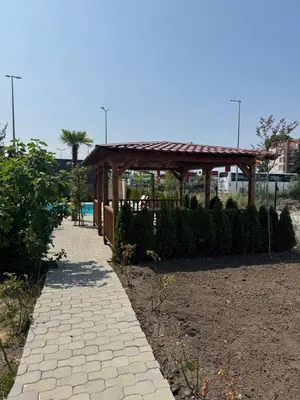 a wooden gazebo in a park with a sidewalk at Студия Магнолия 6, Солнечный берег Болгария in Sunny Beach