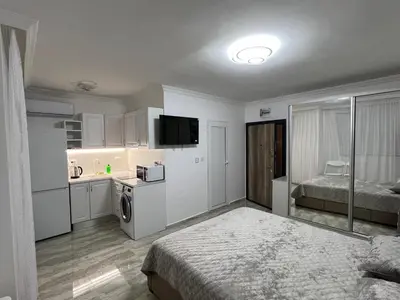 a large white room with a bed and a kitchen at Студия Магнолия 6, Солнечный берег Болгария in Sunny Beach