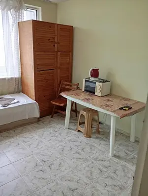 a room with a table with a microwave and a bed at Апартамент планина in Varna City