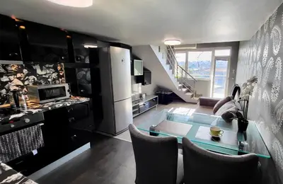 a kitchen and living room with a glass table at Комфорт и стиль - Апартамент с панорамой города in Burgas City
