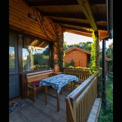 a porch with two benches and a table on it at Бунгала Гнездото Bungalows The Nest Lozenets 2 in Lozenets