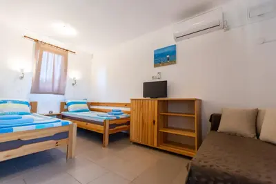a room with two beds and a tv and a couch at Бунгала Гнездото Bungalows The Nest 1 in Lozenets